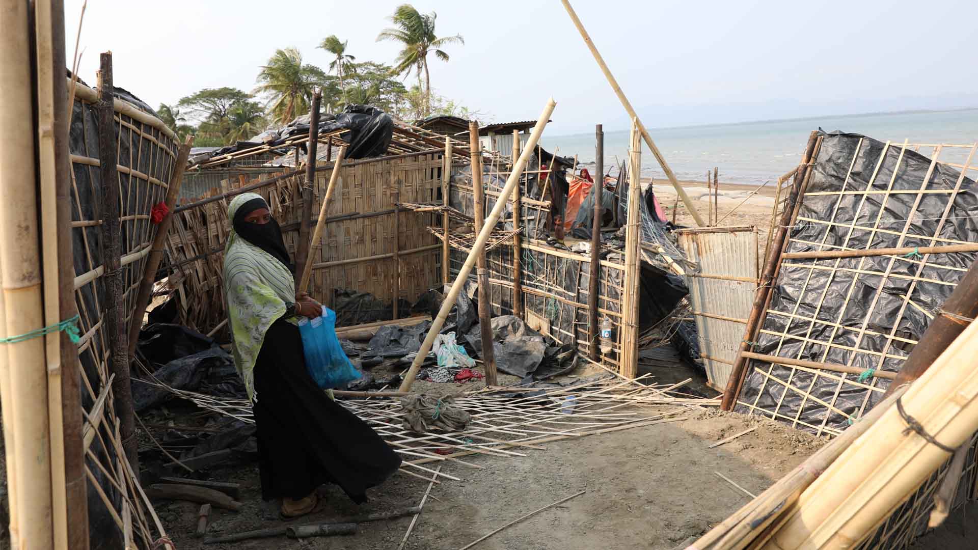 A woman stands to the side of the interior of the remnants of a house that was destroyed by Cyclone Mocha.