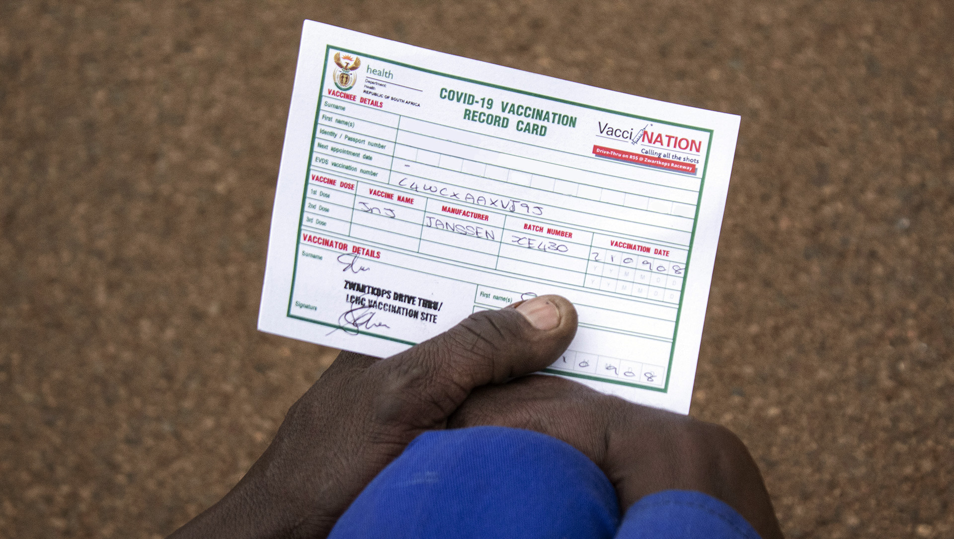 A person holds a vaccination certificate in their hand.