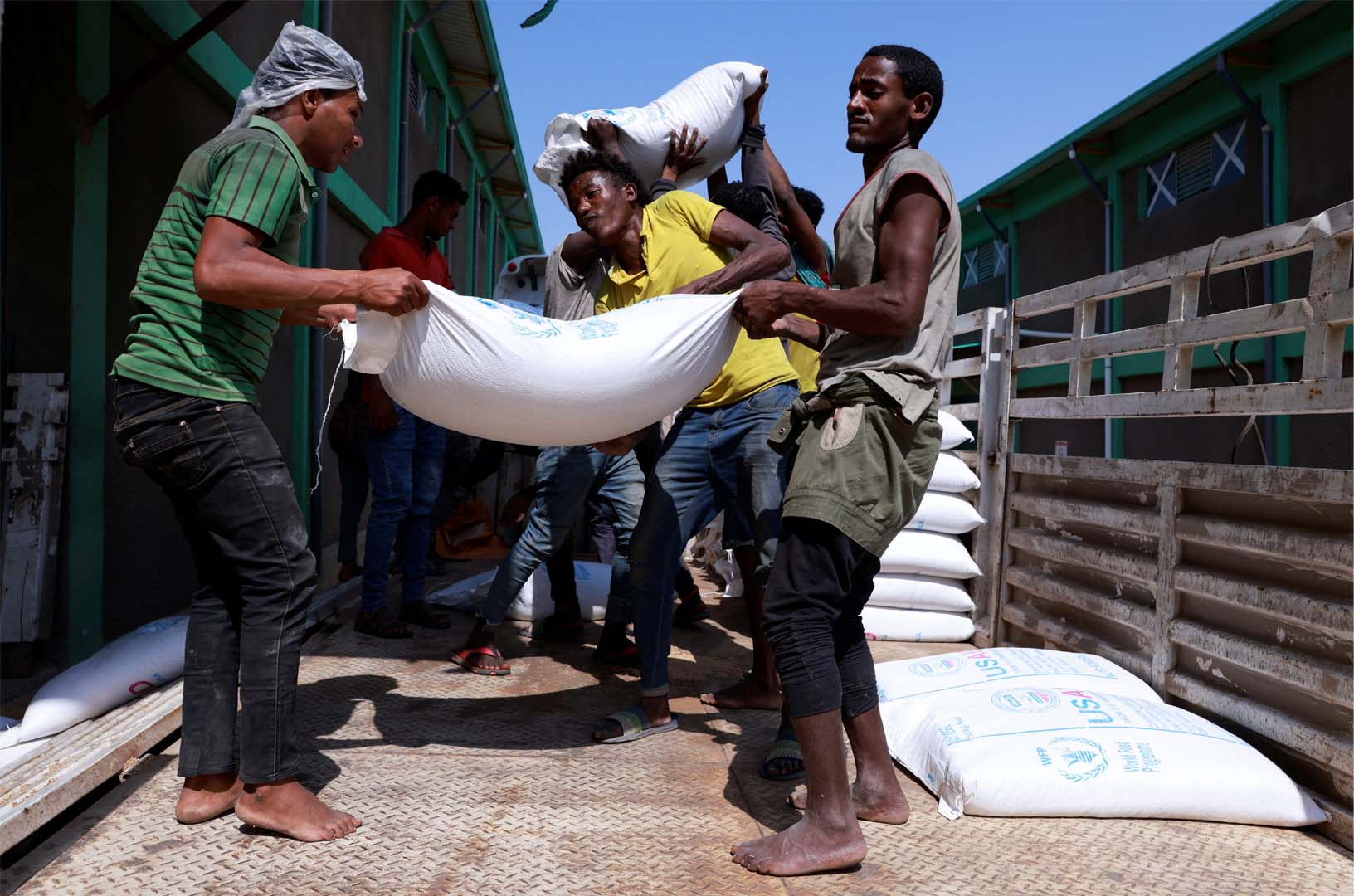 Pictured are a group of men standing in the back of a truck carrying offloading bags of grains as part of relief food that was sent from Ukraine at the World Food Program (WFP) warehouse in Adama town, Ethiopia, September 8, 2022. 